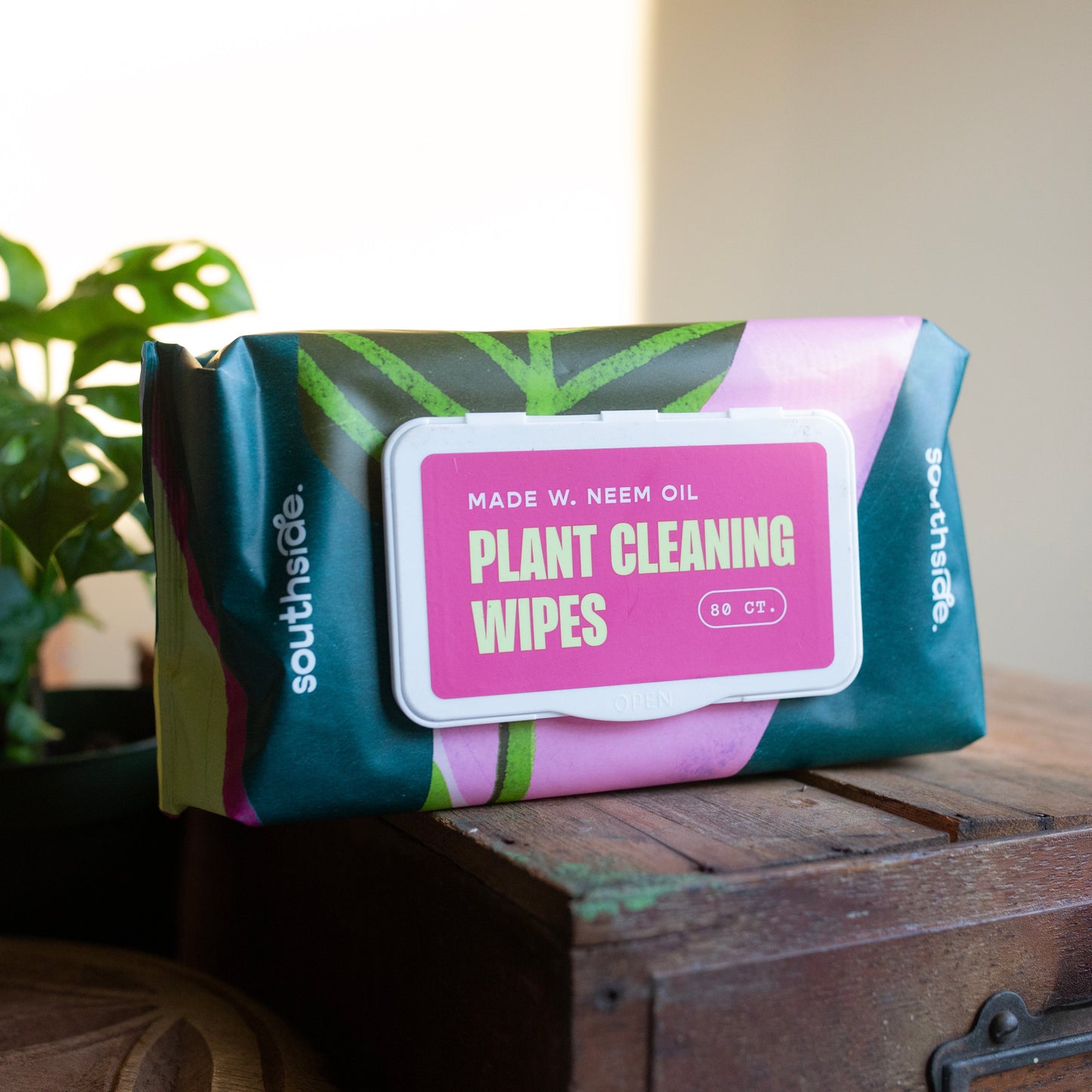 Plant cleaning wipes with bright packaging and abstract leaves. Label reads "made with neem oil; Plant Cleaning Wipes".