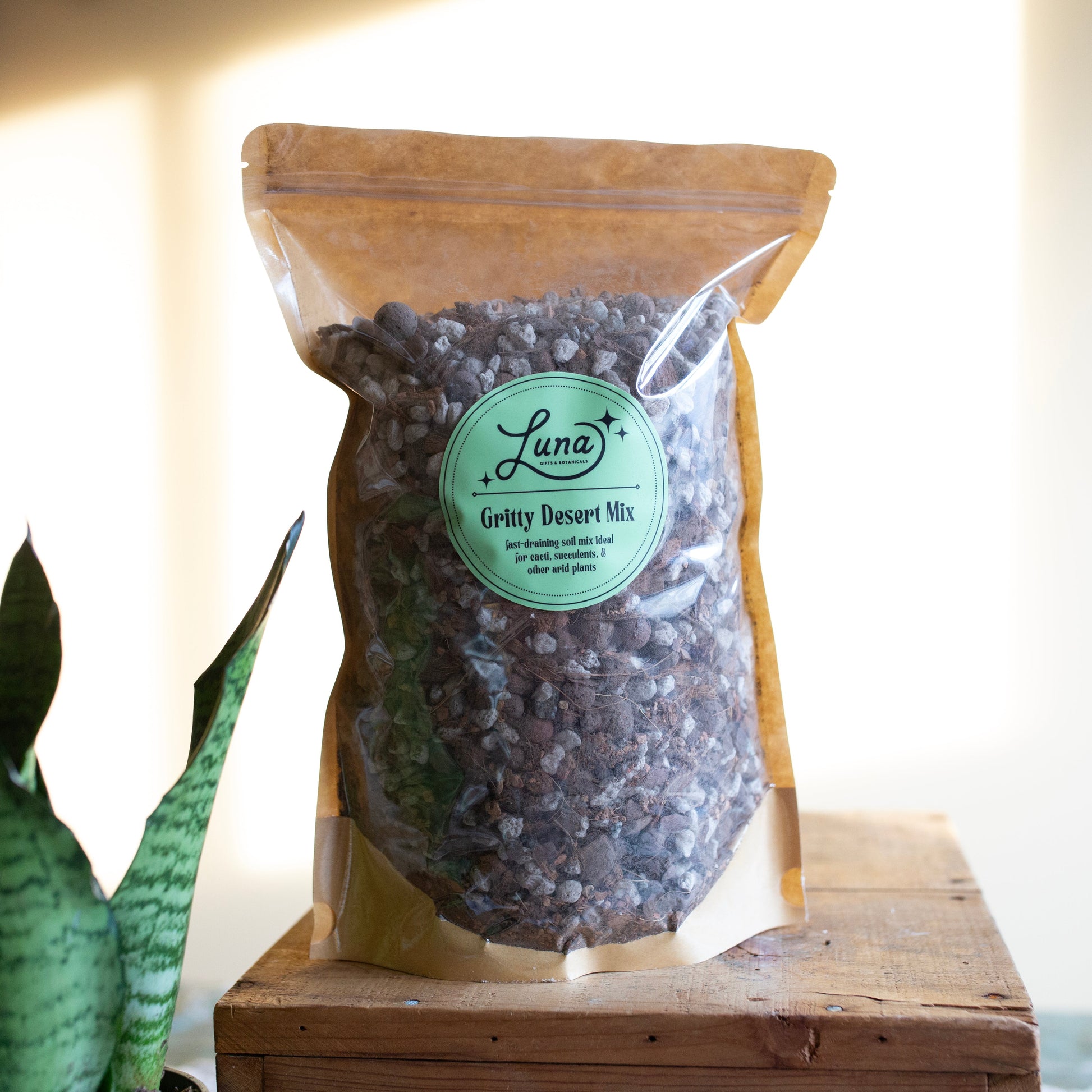 Bag of Luna Gritty Desert Mix on a wooden surface with a plant in the background