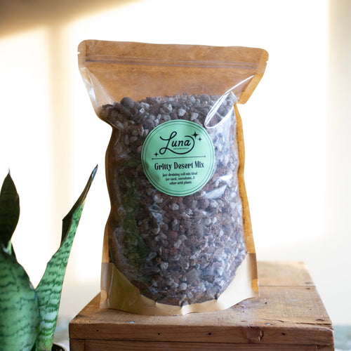 Bag of Luna Gritty Desert Mix on a wooden surface with a plant in the background